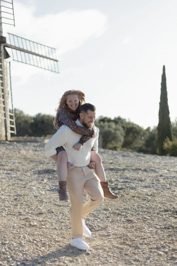 Couple souriant pendant une séance photo près d’un moulin en Provence
