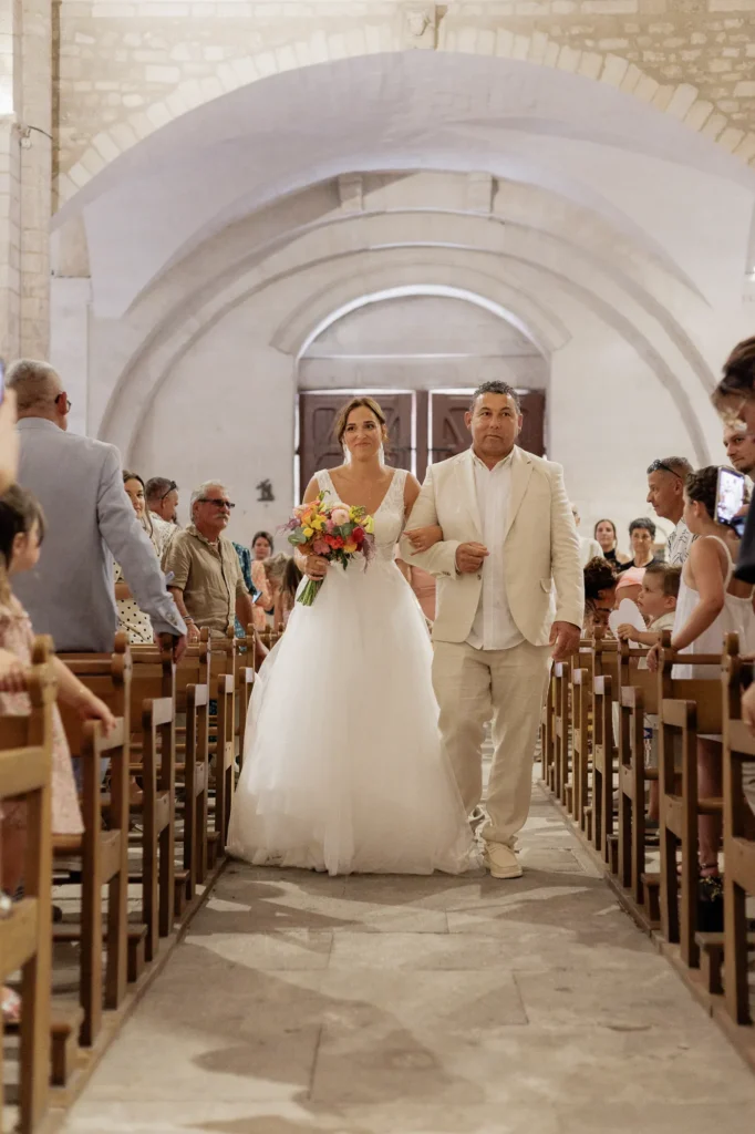 Mariée remontant l’allée de l’abbatiale de Saint-Gilles accompagnée d’un proche
