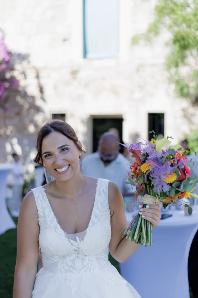 Mariée souriante tenant son bouquet de fleurs colorées pendant le cocktail