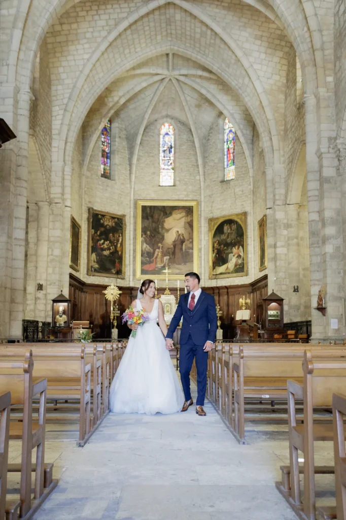 Couple de mariés marchant main dans la main dans l’allée de l’abbatiale de Saint-Gilles