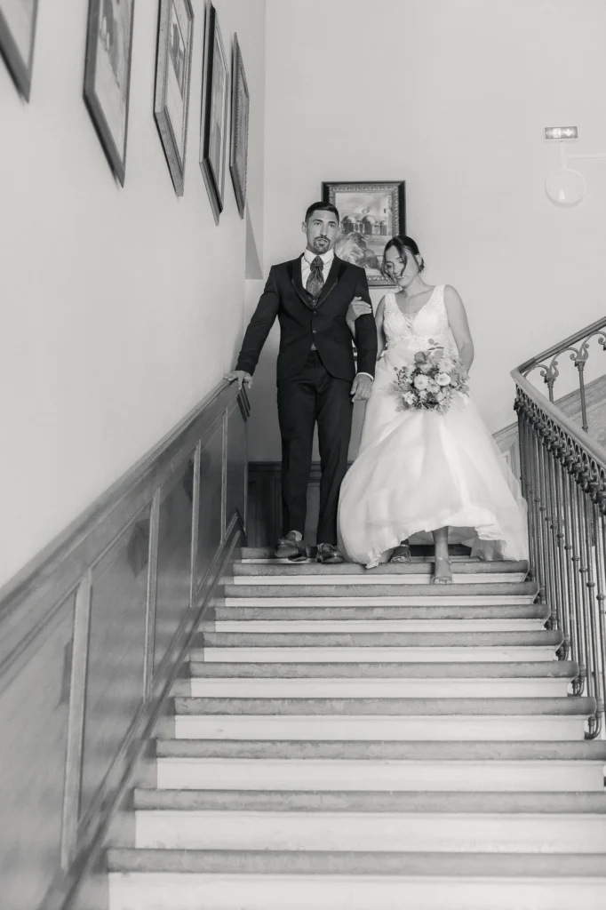 Couple de mariés descendant l’escalier de la mairie photographié en noir et blanc