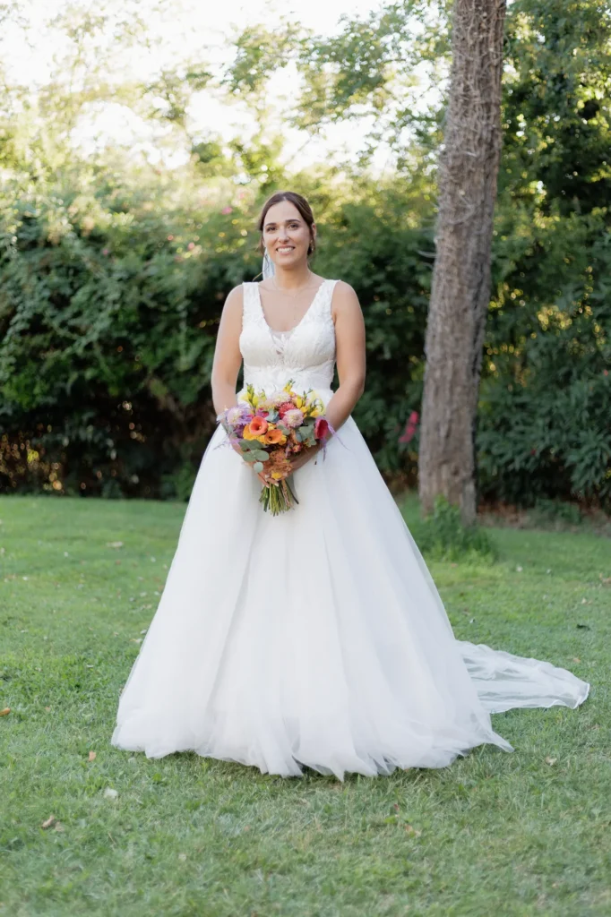 Mariée debout dans le jardin tenant son bouquet de fleurs colorées
