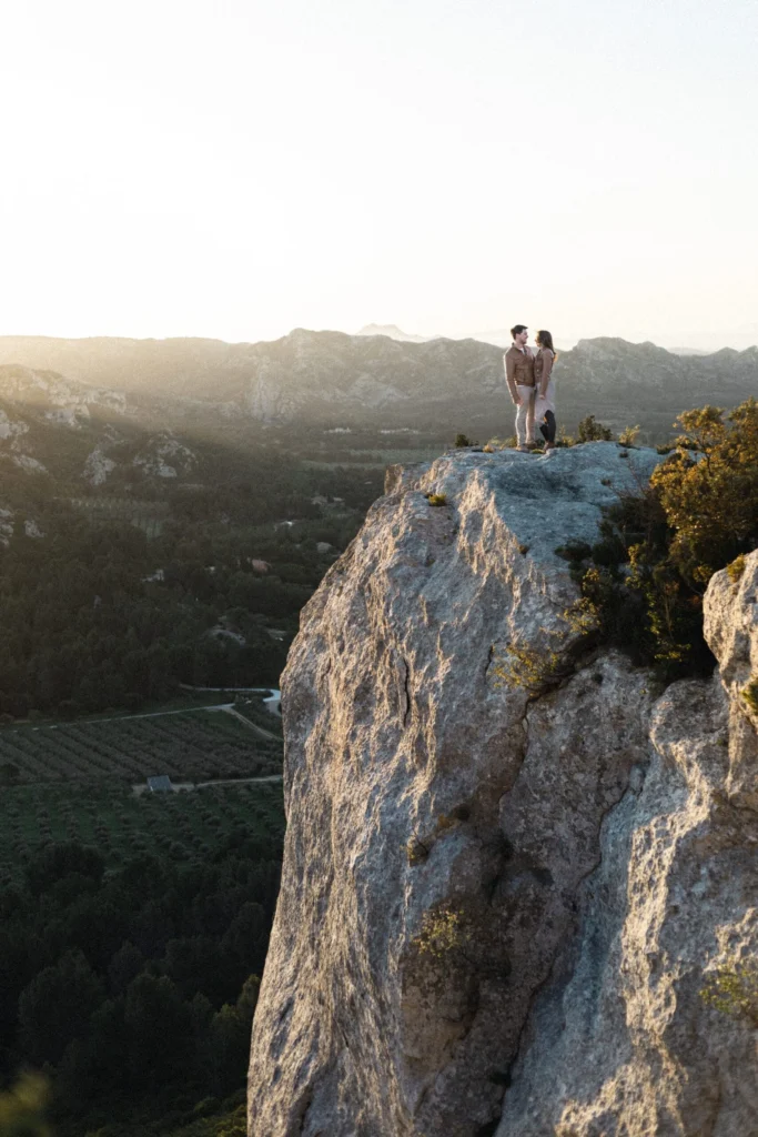 Couple sur un promontoire rocheux face au paysage des Alpilles en Provence
