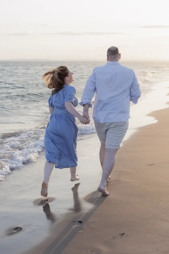 Couple marchant main dans la main sur la plage au coucher du soleil