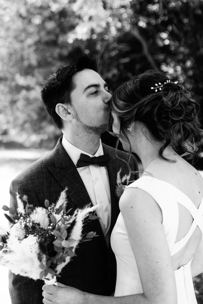 Romain embrasse Mathilde pendant leur first look photographié en noir et blanc