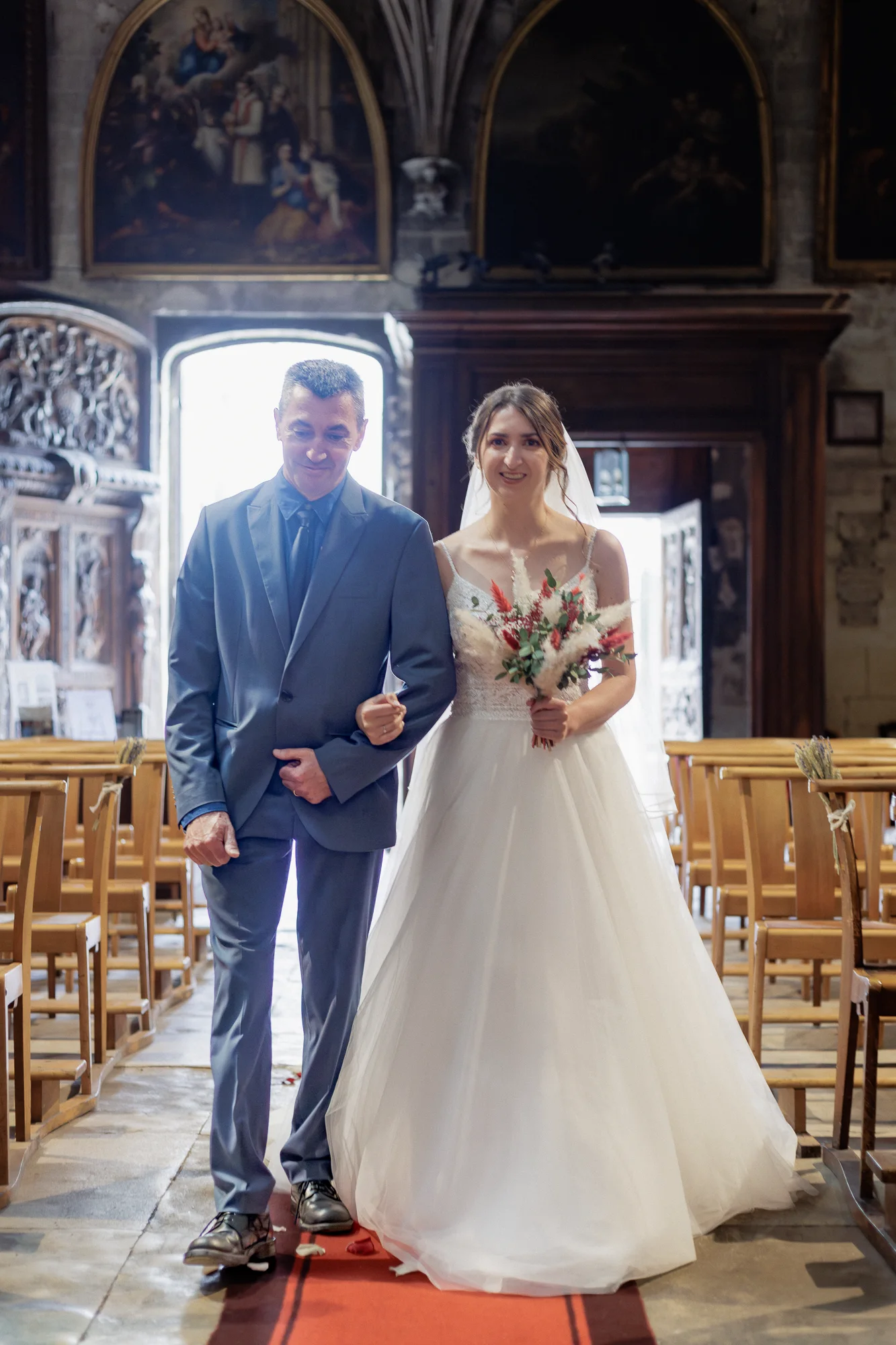 Mathilde entre dans la Basilique Saint-Pierre d’Avignon au bras d’un proche, son bouquet à la main