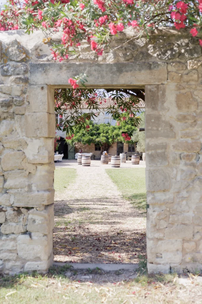 Vue sur la cour du Mas des Tourelles à travers une ouverture dans un mur en pierre